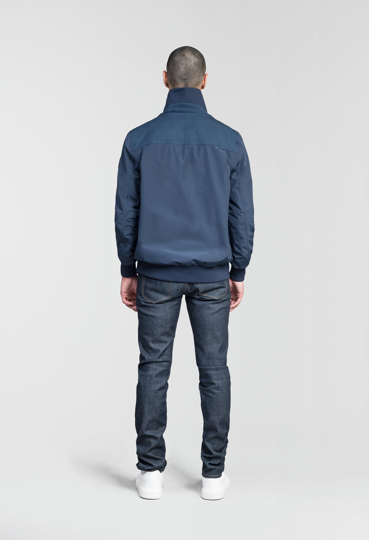 Flint Men's Tailored Rib Collar Jacket in hip length, premium 3-ply Micro Denier fabrication, premium 4-way stretch, water resistant Primaloft Gold Insulation Active +, flap pockets with magnetic closure at waist, side entry pockets at waist, ribbed sleeve cuffs, two-way branded zipper at centre front, box pleat detailing at centre back, large interior zipper pocket, and interior button pocket at left chest, in Marine