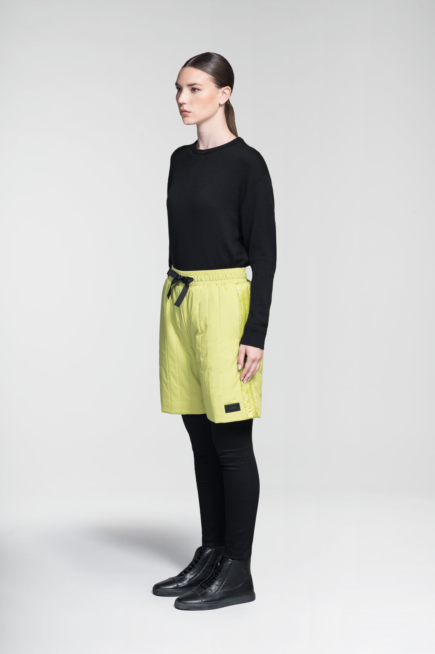 Kit Women's Quilted Shorts in knee length, premium stretch ripstop and contrast cire technical nylon taffeta fabrication, premium 4-way stretch, water resistant Primaloft Gold Insulation Active+, elasticized waistband with grosgrain ribbon drawstrings, hidden side seam toggles for rouching detail, snap closure side seam pockets at hips, and single welt snap button pockets at back, in Black