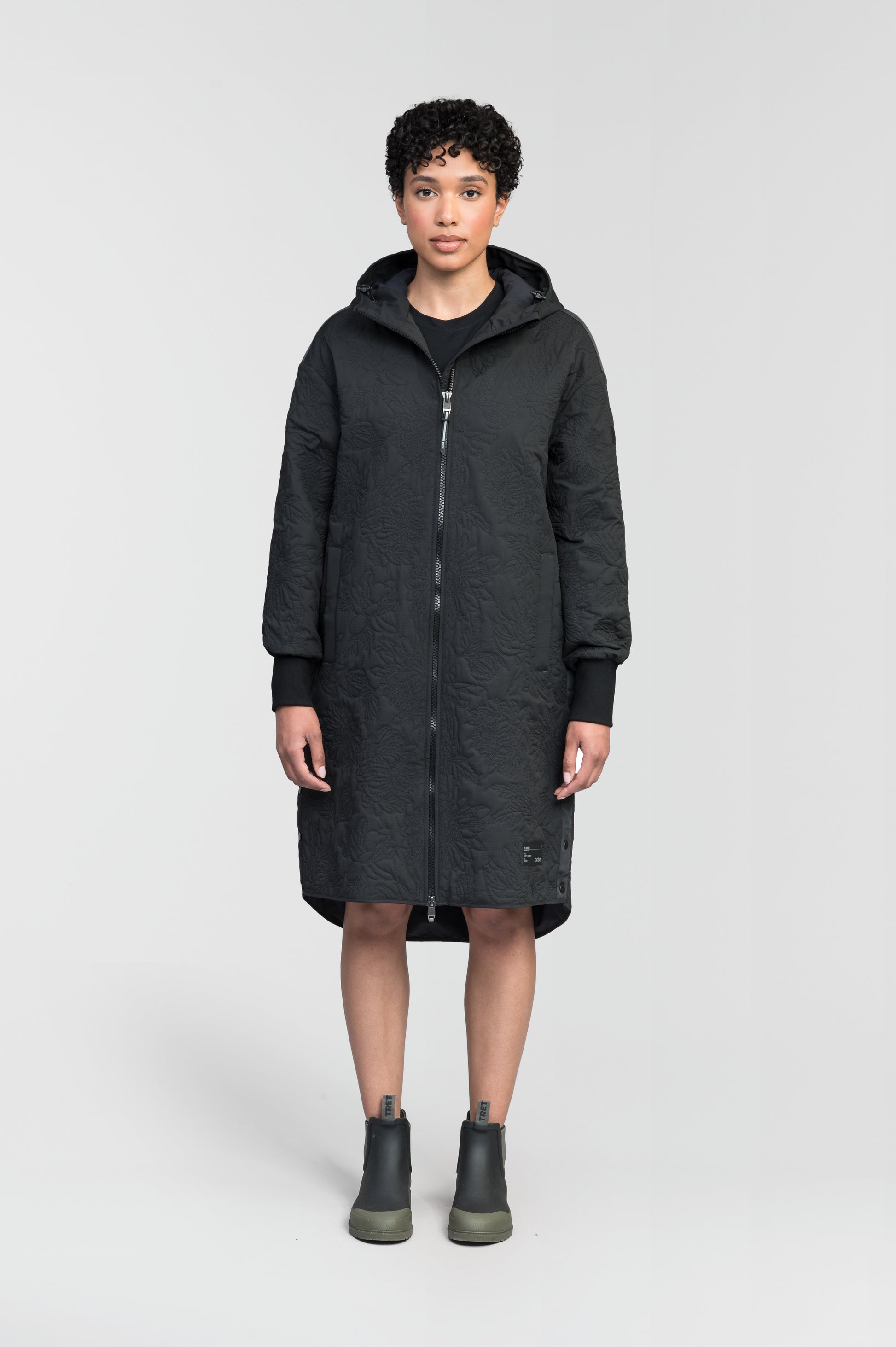 Surrey Women's Performance Quilted Long Mid Layer Jacket in knee length, Primaloft Gold Insulation Active+, non-removable hood, single welt magnetic closure pockets, ribbed cuffs, two-way centre front zipper, grosgrain ribbon detail and shoulders and side seam, and snap closure side seam vents, in Black