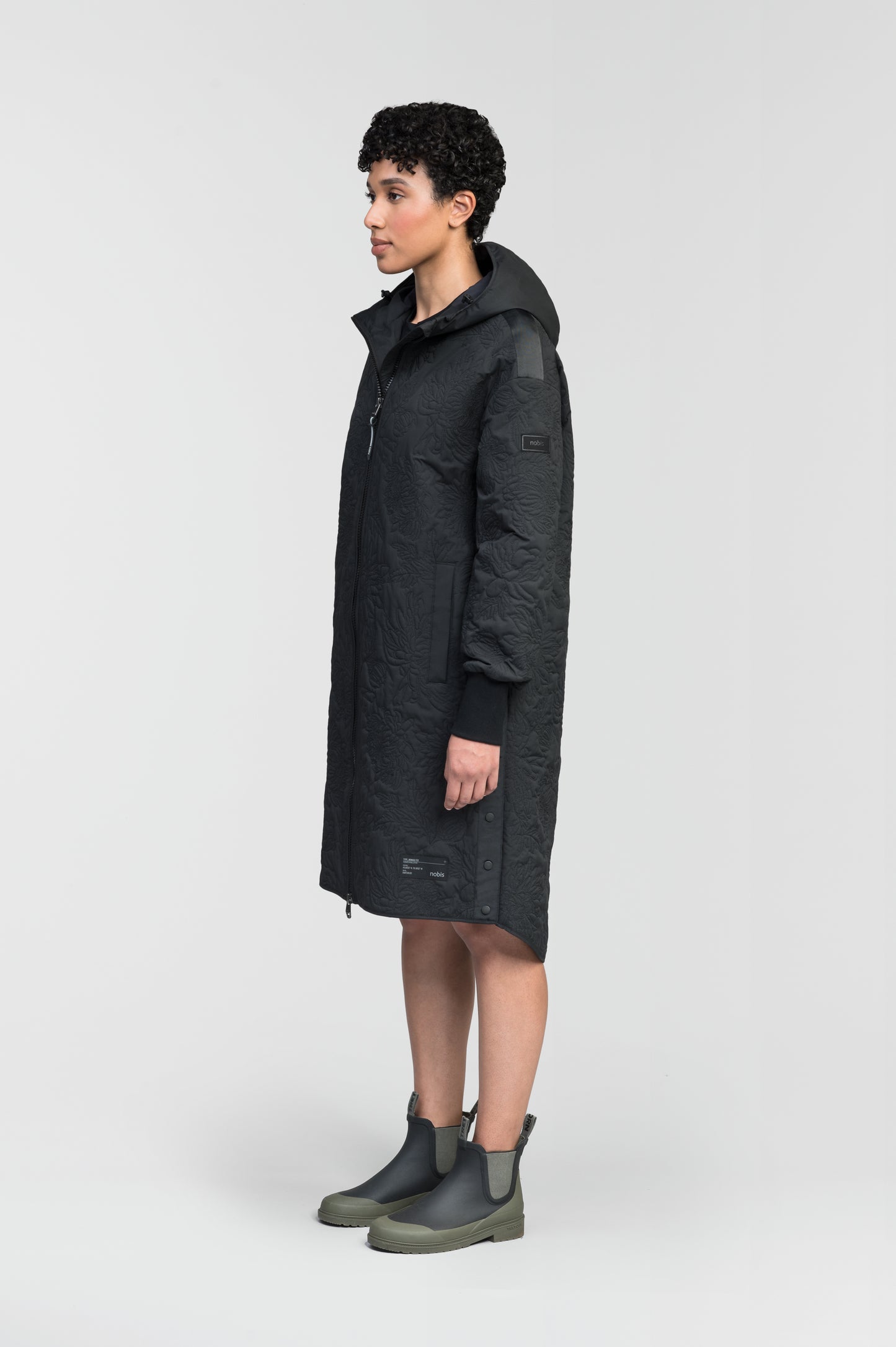 Surrey Women's Performance Quilted Long Mid Layer Jacket in knee length, Primaloft Gold Insulation Active+, non-removable hood, single welt magnetic closure pockets, ribbed cuffs, two-way centre front zipper, grosgrain ribbon detail and shoulders and side seam, and snap closure side seam vents, in Black