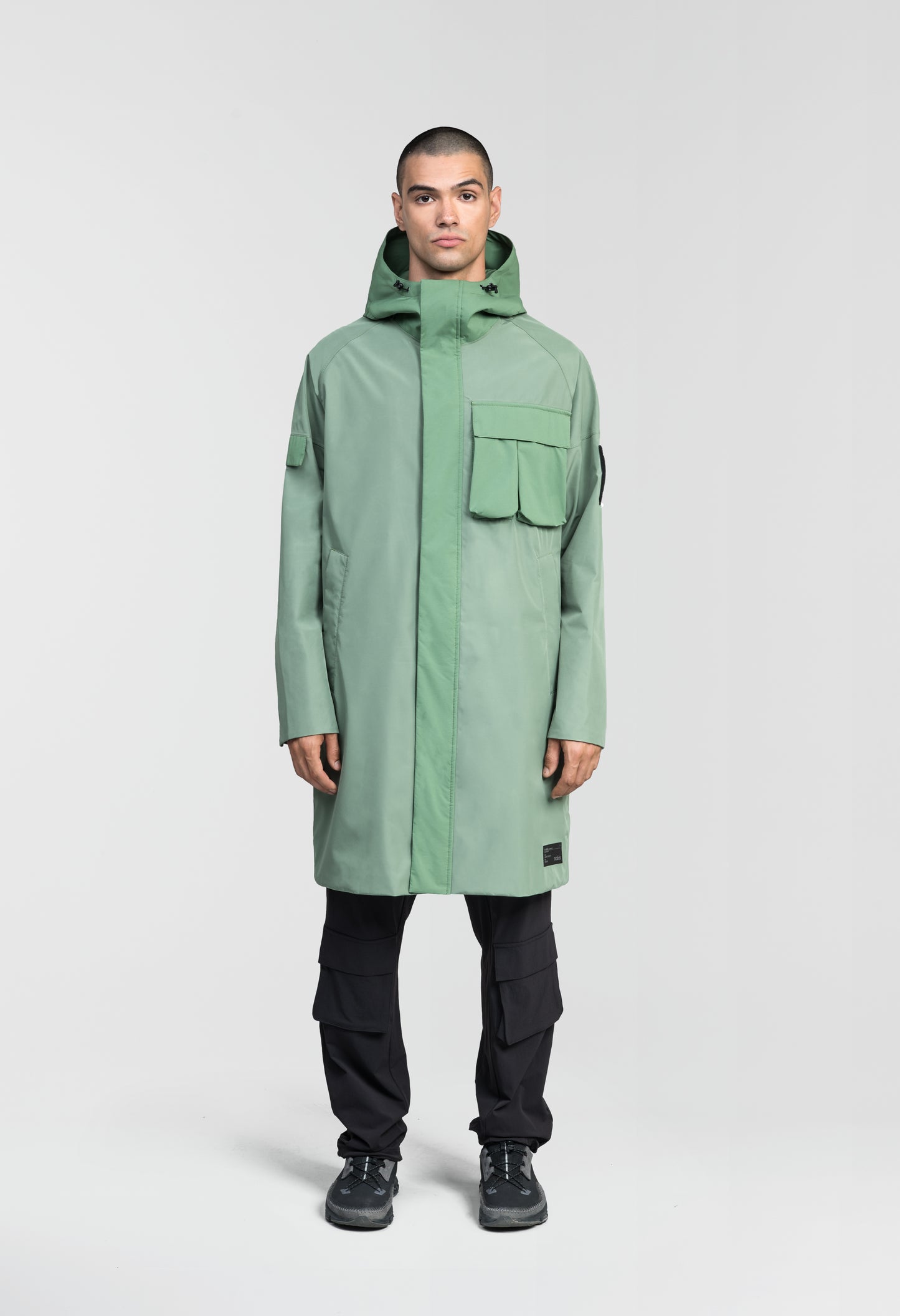 Wylder Men's Performance Rain Jacket in knee length, premium 3-ply Micro Denier and stretch ripstop fabrication, non-removable hood with reflective piping and adjustable draw cord, split utility chest pocket with magnetic flap closure, single welt pockets with magnetic closure at waist, back yoke with mesh ventilation, snap button wind flap, two-way branded zipper at centre front, telescopic sleeves with elasticized cuffs, interior draw cord at waist, in Comfrey
