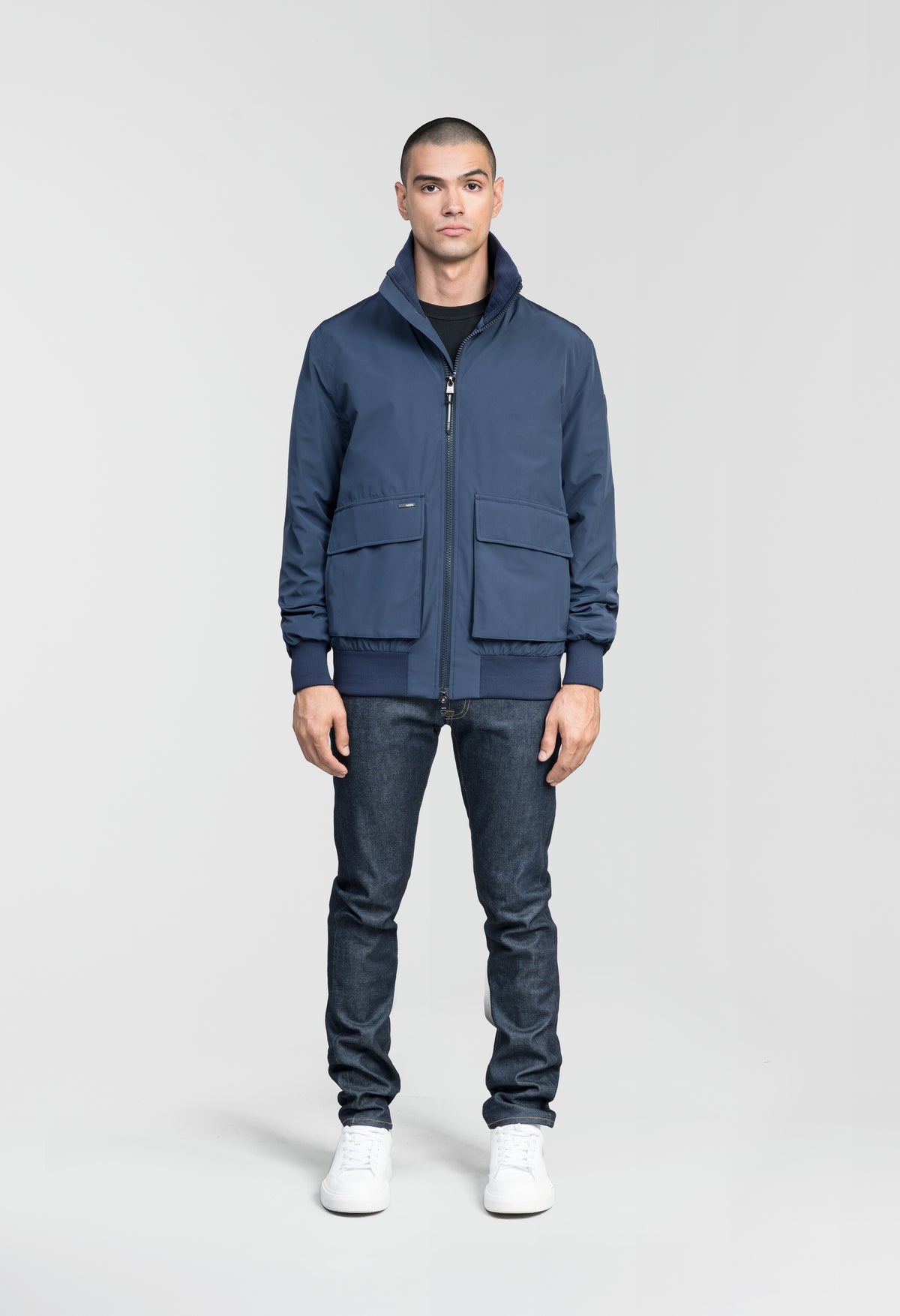 Flint Men's Tailored Rib Collar Jacket in hip length, premium 3-ply Micro Denier fabrication, premium 4-way stretch, water resistant Primaloft Gold Insulation Active +, flap pockets with magnetic closure at waist, side entry pockets at waist, ribbed sleeve cuffs, two-way branded zipper at centre front, box pleat detailing at centre back, large interior zipper pocket, and interior button pocket at left chest, in Marine