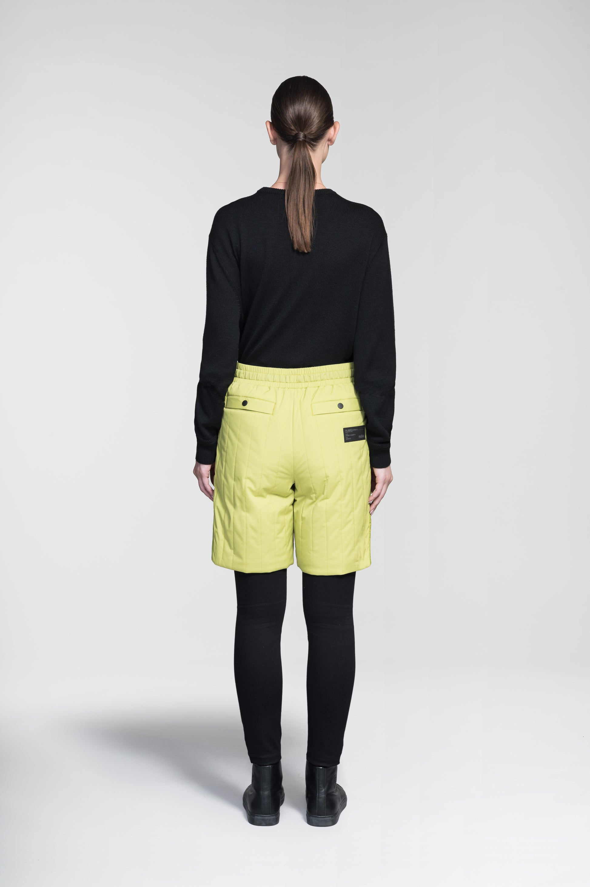 Kit Women's Quilted Shorts in knee length, premium stretch ripstop and contrast cire technical nylon taffeta fabrication, premium 4-way stretch, water resistant Primaloft Gold Insulation Active+, elasticized waistband with grosgrain ribbon drawstrings, hidden side seam toggles for rouching detail, snap closure side seam pockets at hips, and single welt snap button pockets at back, in Black