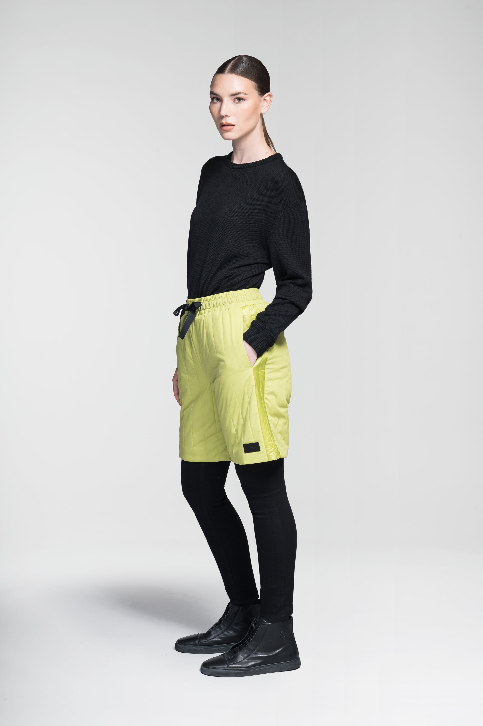 Kit Women's Quilted Shorts in knee length, premium stretch ripstop and contrast cire technical nylon taffeta fabrication, premium 4-way stretch, water resistant Primaloft Gold Insulation Active+, elasticized waistband with grosgrain ribbon drawstrings, hidden side seam toggles for rouching detail, snap closure side seam pockets at hips, and single welt snap button pockets at back, in Black