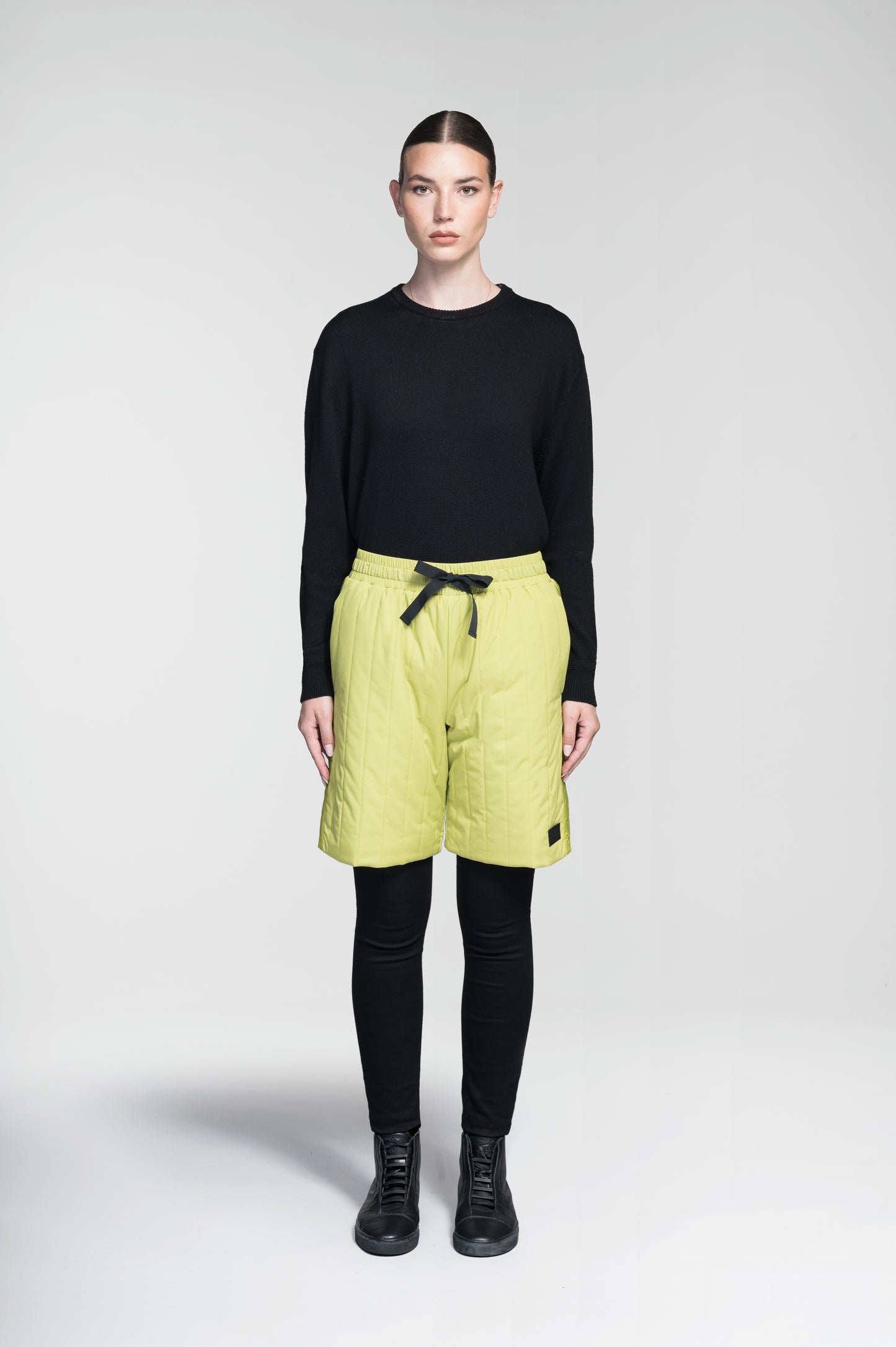 Kit Women's Quilted Shorts in knee length, premium stretch ripstop and contrast cire technical nylon taffeta fabrication, premium 4-way stretch, water resistant Primaloft Gold Insulation Active+, elasticized waistband with grosgrain ribbon drawstrings, hidden side seam toggles for rouching detail, snap closure side seam pockets at hips, and single welt snap button pockets at back, in Black