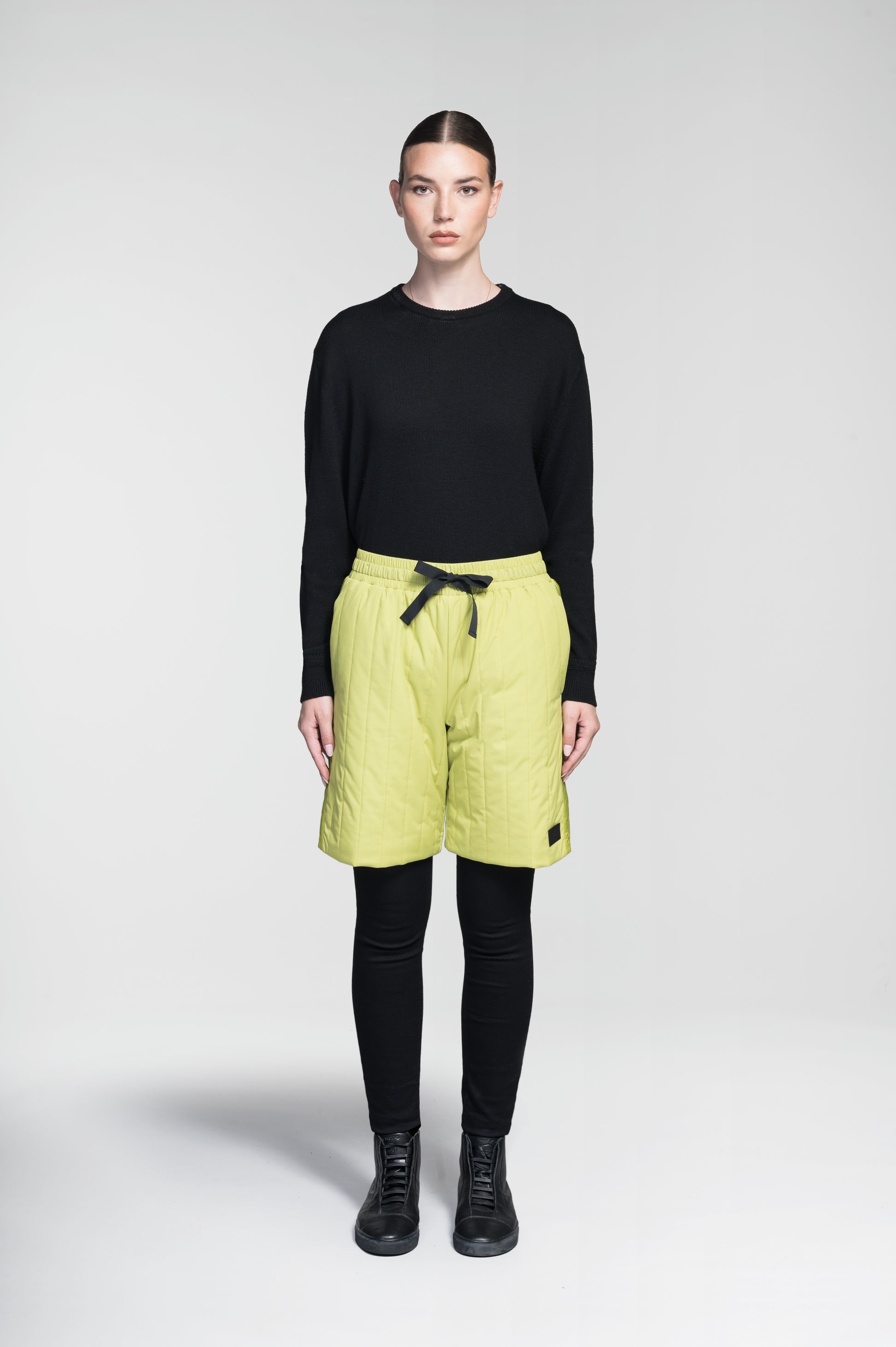 Kit Women's Quilted Shorts in knee length, premium stretch ripstop and contrast cire technical nylon taffeta fabrication, premium 4-way stretch, water resistant Primaloft Gold Insulation Active+, elasticized waistband with grosgrain ribbon drawstrings, hidden side seam toggles for rouching detail, snap closure side seam pockets at hips, and single welt snap button pockets at back, in Black