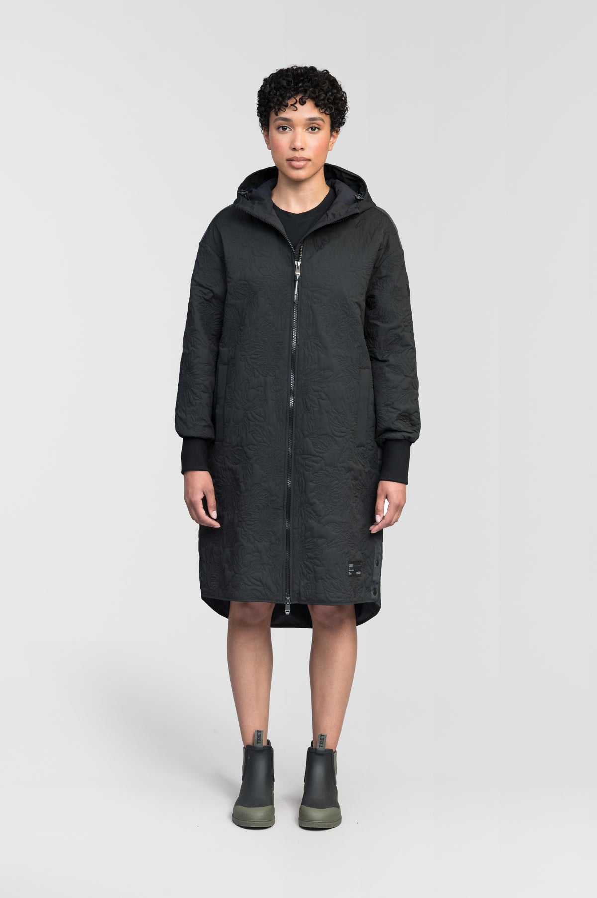 Surrey Women's Performance Quilted Long Mid Layer Jacket in knee length, Primaloft Gold Insulation Active+, non-removable hood, single welt magnetic closure pockets, ribbed cuffs, two-way centre front zipper, grosgrain ribbon detail and shoulders and side seam, and snap closure side seam vents, in Black