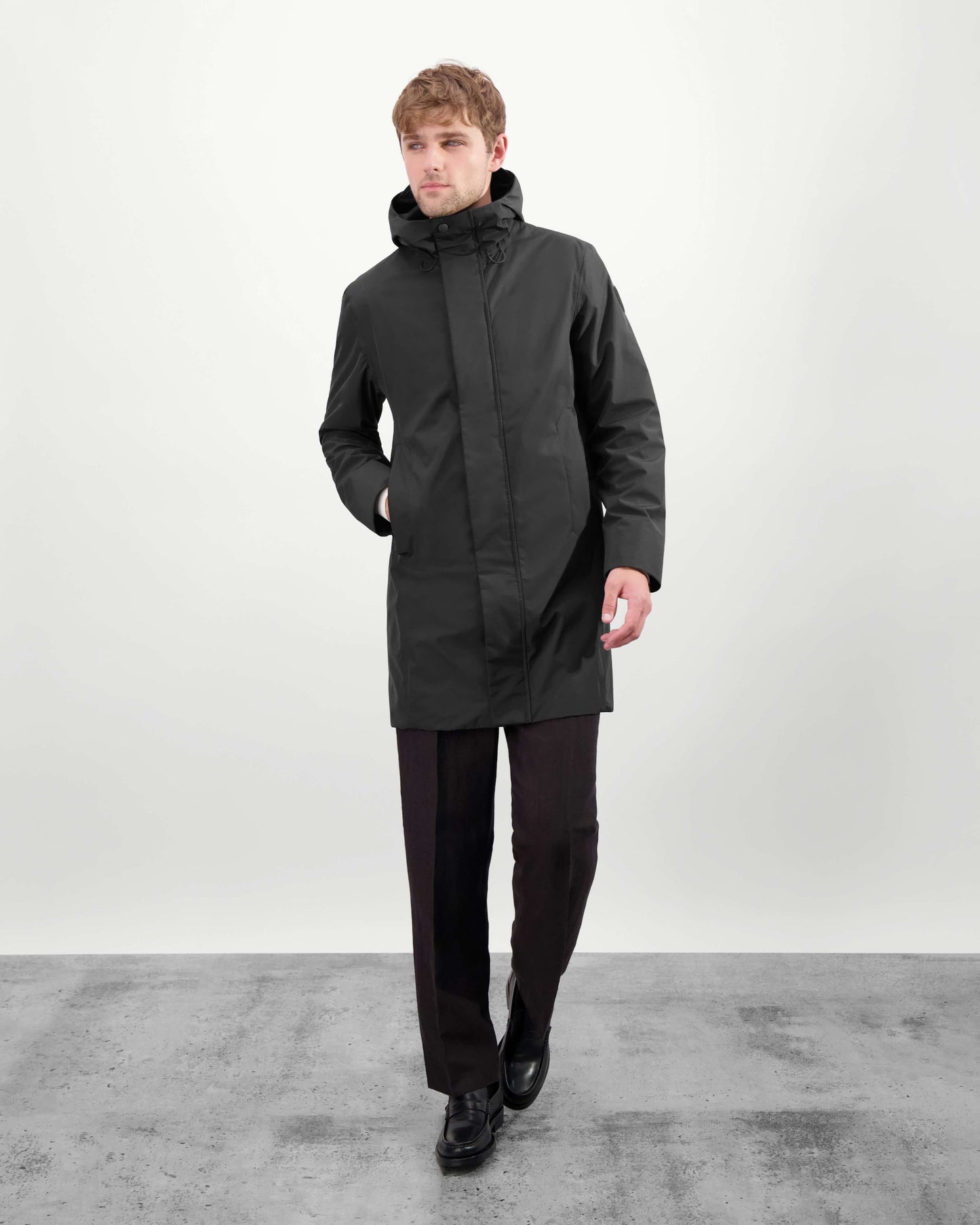 Upton long jacket in Black in 3-ply Micro Denier fabric with DWR coating, featuring a two-way zipper with magnetic closure, hidden mesh ventilation, and underarm vents. Designed for weather protection and tailored comfort.