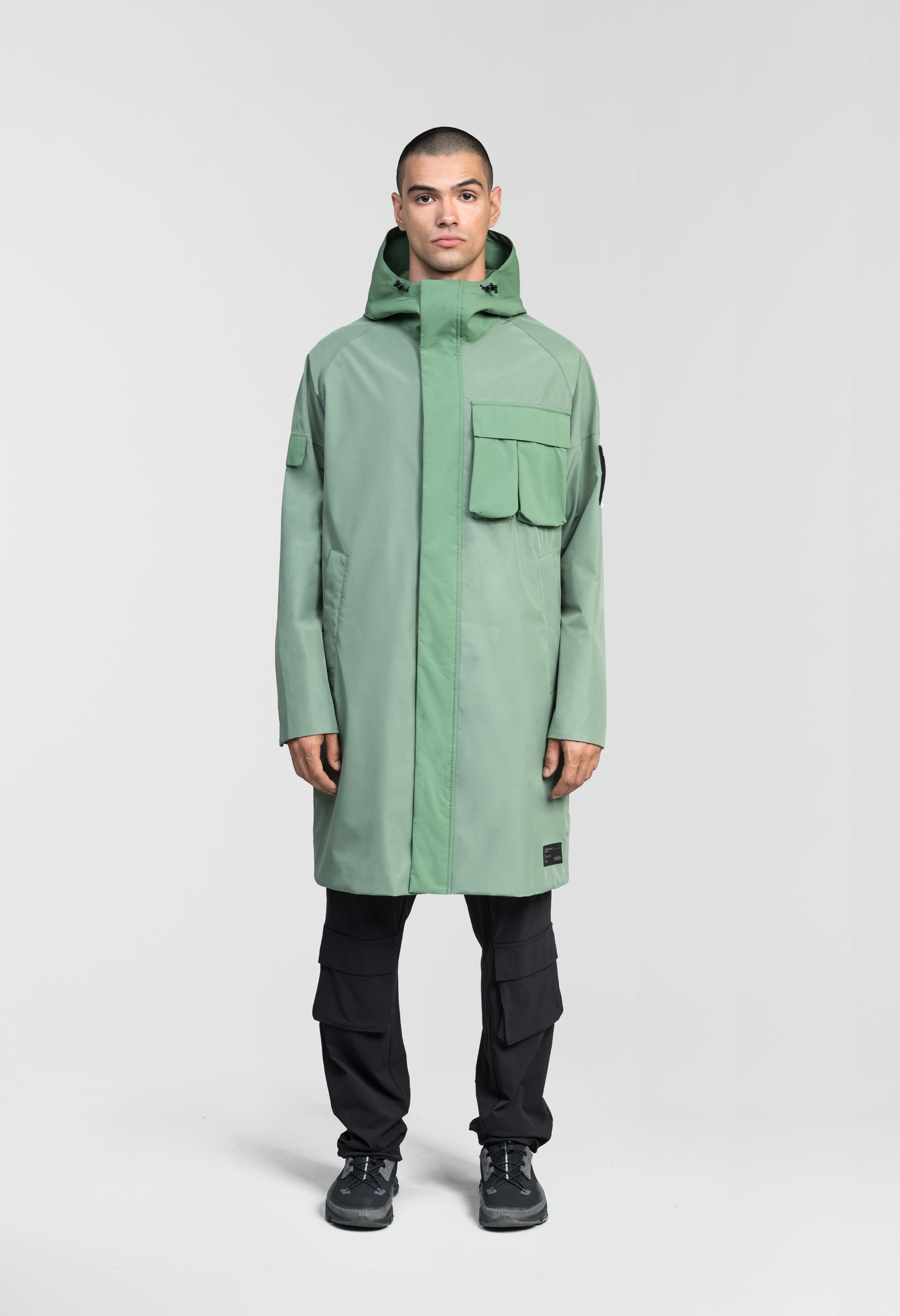 Wylder Men's Performance Rain Jacket in knee length, premium 3-ply Micro Denier and stretch ripstop fabrication, non-removable hood with reflective piping and adjustable draw cord, split utility chest pocket with magnetic flap closure, single welt pockets with magnetic closure at waist, back yoke with mesh ventilation, snap button wind flap, two-way branded zipper at centre front, telescopic sleeves with elasticized cuffs, interior draw cord at waist, in Comfrey