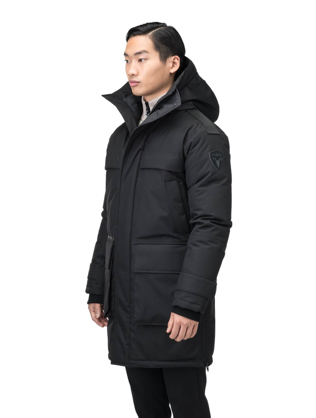 Alum Men's Long Parka in thigh length, Premium Canadian White Duck Down insulation, non-removable hood with removable coyote fur trim, two-way centre front zipper with magnetic closure wind flap, four exterior patch pockets at front, in Black